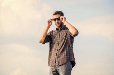 Erkek gözlüklü model açık havada mavi gökyüzü arka planı. Mükemmel görüş. Moda uzmanı. Yakışıklı adam güneş gözlüğü takıyor. Moda güneş gözlüklü hippi. Modaya uygun güneş gözlükleri. Ultraviyole koruma kavramı