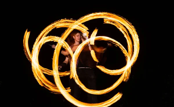 Un par de artistas del fuego crean patrones ardientes girando pois ardiendo en la oscuridad nocturna al aire libre, arte —  Fotos de Stock