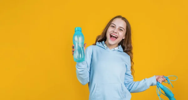 Felice sorridente bambina tenere sport o attrezzature per il fitness di corda da salto e bottiglia d'acqua, salute — Foto Stock