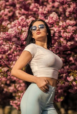 Sakura, kiraz çiçeği ağacı. Seksi kız sakura çiçeğinin tadını çıkarıyor. Kiraz çiçekli kadın. Çiçekli güzel bayan. Doğa Saç Tarzı. Tatil Moda Makyajı. Yaz romantik imajı