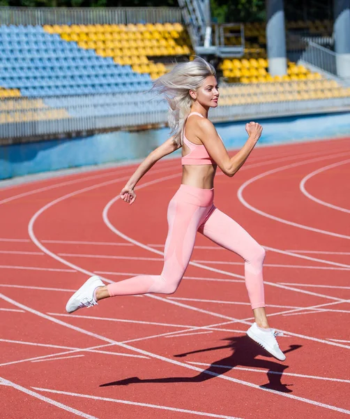 体格健壮的女士穿着运动服在体育场赛马场跑步，同时进行体育锻炼、耐力锻炼 — 图库照片