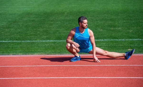 Hombre maduro estirando sus piernas antes de un entrenamiento en el estadio, estirar — Foto de Stock