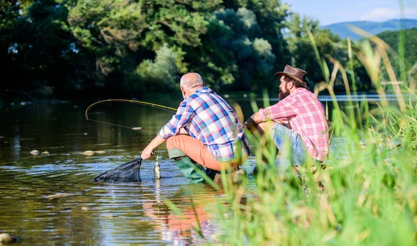 Dos amigos pescando juntos. pesca de caza mayor. relajarse en la naturaleza. feliz amistad de pescadores. padre jubilado e hijo barbudo maduro. pasatiempo peces mosca de los hombres. pesca de jubilación. Lo hemos cogido. —  Fotos de Stock