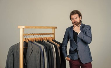 Takım elbiseli adam. Atölyesindeki terzi. Klasik kostüm giymiş yakışıklı sakallı moda adamı. Özel dikim takım elbiseli bir adam özel dikim smokin giyiyor. Butikte erkek kıyafetleri. Tasarımı mükemmel.