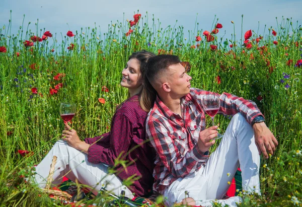 Chłopak i dziewczyna mając romantyczną randkę na polu maku kwiat z gitara muzyka i wino, data — Zdjęcie stockowe