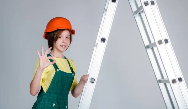 Mädchen mit Helm spielt Bauarbeiterin. Gebäude und Renovierung. Kinder bauen Konstruktionen. Ingenieur ist Bauarbeiter. Weltarbeitertag. Elektriker auf Trittleiter — Stockfoto