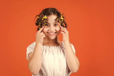 Dinlen biraz. Güzellik ve moda. Küçük kızın bigudileri var. Çocuk kuaför salonu. Sağlıklı, uzun saç stili. Çocuk için saç bakımı. Saçlarını yuvarlayan küçük bir kadın. Göz tedavisi bandı