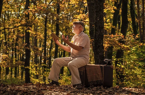 Pensionista feliz relaxar na natureza outono. Viagens de aposentadoria e hobbies. Ecologia. Homem maduro segurar folhas amarelas. Fotógrafo examina folhas de outono. Natureza no Outono. Temporada de Outono. ecologista qualificado — Fotografia de Stock