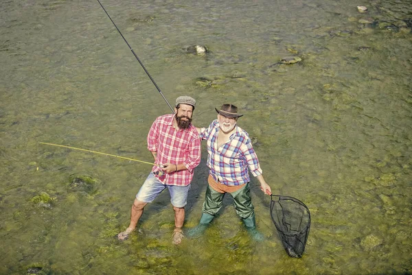 A trabalhar juntos. Fim de semana. homens maduros pescador. amizade masculina. ligação familiar. pesca de pai e filho. hobby e atividade esportiva. Isca de truta. dois pescadores felizes com vara de pesca e rede — Fotografia de Stock