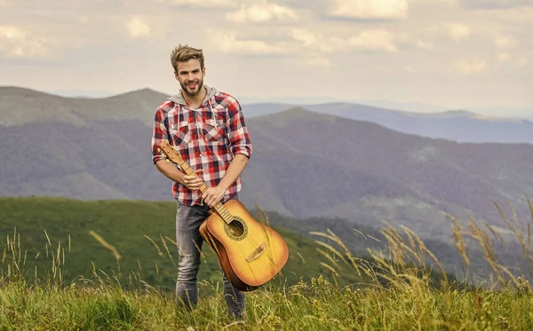 Cisza gór i dźwięk strun gitarowych. Hipsterski muzyk. Inspirujące środowisko. Letni festiwal muzyki na świeżym powietrzu. Włączam muzykę. Człowiek muzyk z gitarą na szczycie góry. Inspirujący muzyk — Zdjęcie stockowe