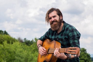 Tişörtlü, beyaz, vahşi hippi akustik gitar çalıyor.
