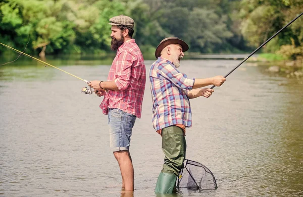 Far og sønn som fisker. Fiskeutstyr. Fiskerbestefar og modne mannevenner. Fiskerfamilie. Hobbys sportsaktivitet. Sommerhelg. Fredelig aktivitet. Bra fanget. Stropp og takle – stockfoto