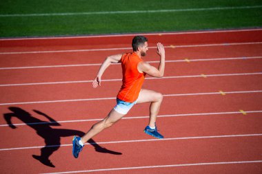 İçinde enerji var. Yarış pistinde koşucu. Meydan okuma ve rekabet. Maraton hızı. Sporcu sporcu kazanmak için hızlı koşar. Başarılı fitness koşucusu. Stadyumdaki koşu pistinde erkek koç. Dayanıklılık ve dayanıklılık