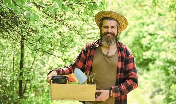 나무 상자가 있는 밀짚 모자를 쓴 농부. 온실에서 일하는 성숙 한 남자 정원사. 잔인 한 수컷은 정원 도구를 가지고 다닌다. 인간과 자연. 농업과 꽃의 개념입니다. 봄 계절 — 스톡 사진