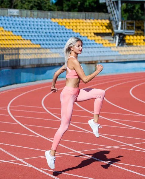 Spor giyimli bir kadın antrenman öncesi stadyumda koşuyor. Dayanıklılık ve dayanıklılık. — Stok fotoğraf