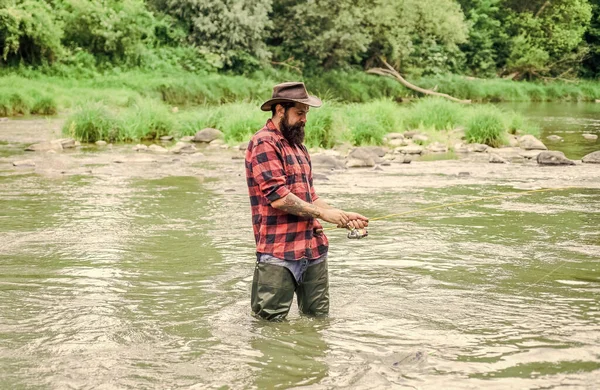 Homem brutal usar botas de borracha ficar na água do rio. Pescador satisfeito. A pesca requer que você esteja atento e plenamente presente no momento. Passatempo masculino Fisher. Equipamento de pesca Fisher. Peixe no anzol — Fotografia de Stock