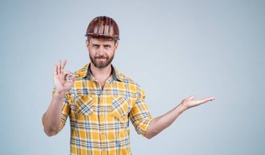 İnşaat kasklı yakışıklı tamirci ve inşaat sahasında kareli gömlek. Ürünü sunuyor. Jest, kopyalama alanı, kalite...