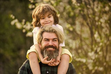 Aile zamanı. Bahar geliyor. Eğlenmene bak. Aşk konsepti. Neşeli baba parkta çocuğuyla oynuyor. Yakışıklı bir baba ve tatlı bir oğlu var. Çiçek ve doğanın tadını çıkarın. Mutlu aile günleri.