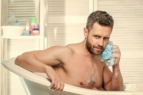 Mężczyzna myje muskularne ciało gąbką z pianki. Macho nagi w wannie. Koncepcja seksu i relaksu. osobistej opieki. Seksowny facet w łazience. Ostrożnie zmyć pianę wodą. przystojny w kąpieli bąbelkowej — Zdjęcie stockowe