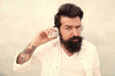 Mükemmel bir fikir. Elektronik dans müziği ve ev şarkıları. Enstrümantal müzik. Sakallı adam kulaklıkları arka planda. Hippi müzik kulaklığı dinler. Modern kablosuz kulaklıklar