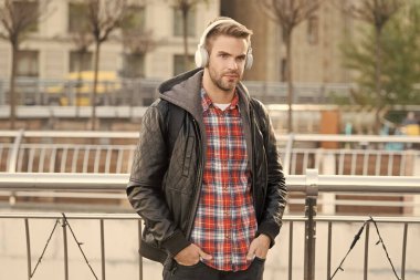 Modern tarzda. Yakışıklı adam şehir dışında kulaklık takıyor. Genç adam modern müzik dinler. Modern müzik teknolojisi. Çağdaş müzik. Yeni teknoloji. Modern hayat
