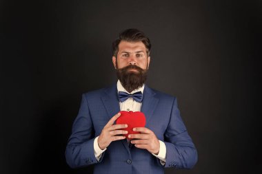 Sevgililer Günü. Yakışıklı sakallı adam smokin giyer. Romantizm ve flört. Centilmen romantik ruh. Adam sevginin kalp sembolünü taşıyor. Randevu servisi. Centilmen kavramı. Gerçek beyefendi.