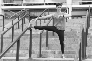 Erkek koşucu esneme egzersizi yapıyor. Şehir ortamında genç bir adamın egzersizi. Bacakları uzanıyordu. En iyi sonucu elde etmek. İlk önce ısınalım. sağlıklı yaşam ve kendini kontrol kavramı