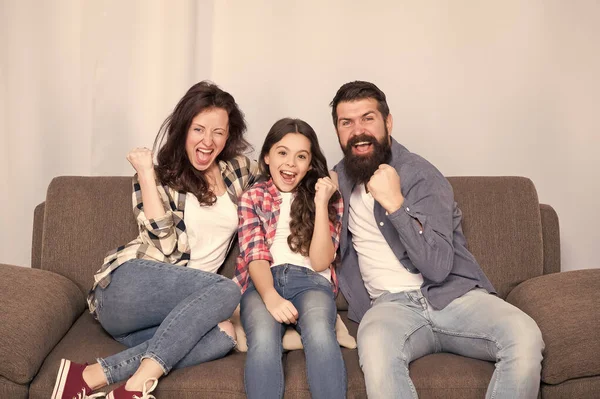 Quédate en casa. La familia se sienta en el sofá. Feliz padre, madre e hija. Concepto de cuarentena y aislamiento. Familia sonriente. La unidad es nuestro poder. Fin de semana finalmente. Niña relajándose con los padres — Foto de Stock