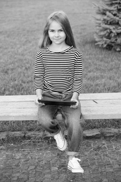 Actividades en línea para mantener a los niños ocupados. Pequeño bebé use la tableta sentada en el banco del parque. Jugar en línea juegos divertidos. Navegación por Internet. Nueva tecnología. La vida moderna. Vacaciones de verano. Su tiempo historia en línea — Foto de Stock