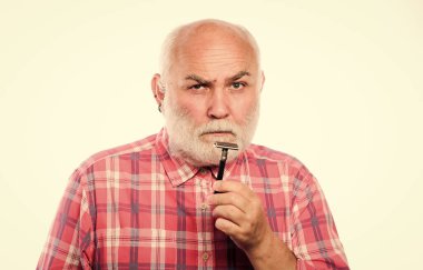 Berber dükkanı konsepti. Traş aksesuarları. Kes ve saç fırçala. Beyaz sakallı, olgun bir adam. Tıraşsız yaşlı adamın bıyığı ve sakalı var. Tıraş bıçağı alet çantası. Elektrikli jiletle tıraş olmak.