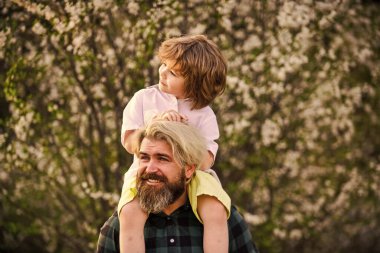 Çok mutluyum. Yakışıklı bir baba ve tatlı bir oğlu var. Çiçek ve doğanın tadını çıkarın. Mutlu aile günleri. Bahar geliyor. Eğlenmene bak. Aşk konsepti. Neşeli baba parkta çocuğuyla oynuyor.