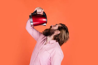 Hayattaki modern teknoloji. Sakallı hippi ev aletleri kullanır. Mutfak konsepti Bıyıklı vahşi yakışıklı adam çay içiyor. Olgun koca elektrikli su ısıtıcısı tutuyor.