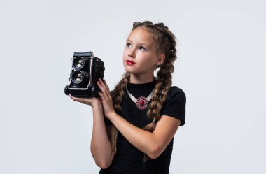 Retro kameralı şık bir çocuk beyaz fotoğraflarla izole edilmiş bir fotoğraf çekiyor.