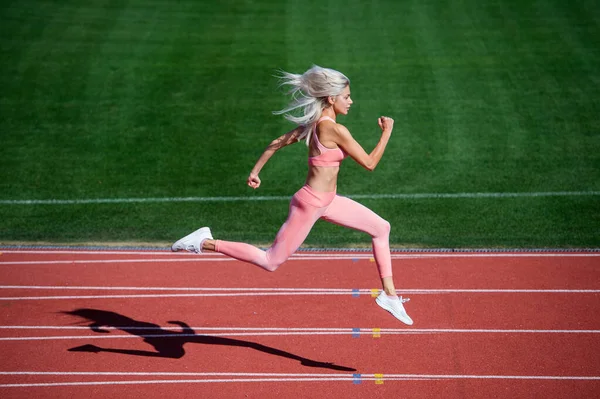 Passform dam i fitness slitage kör på stadion racetrack medan sport träning, energi — Stockfoto