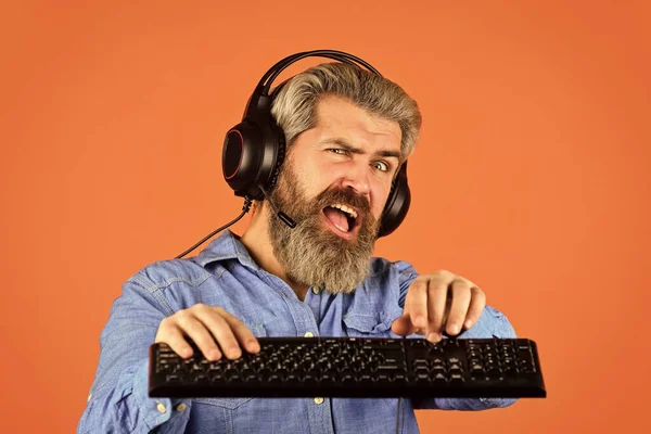 Superior performance. Online gaming. Modern leisure. Run any modern game. Graphics settings pushed to limit. Play computer games. Man bearded hipster gamer headphones and keyboard. Gaming addiction