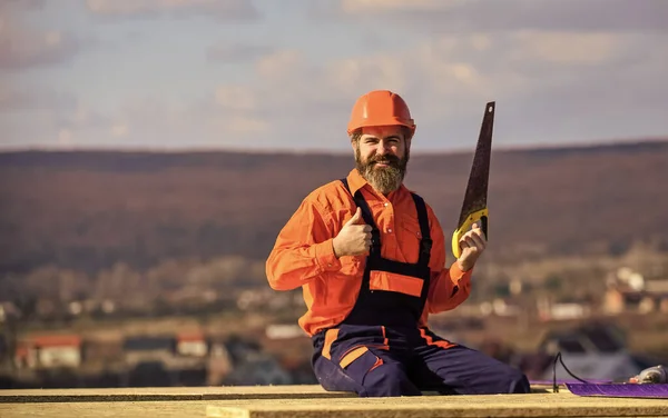 Construction carpentry. Man builder wear uniform and hard hat for protection. Carpentry concept. Hard labour on sunny day outdoors. Bearded construction worker. General construction experience