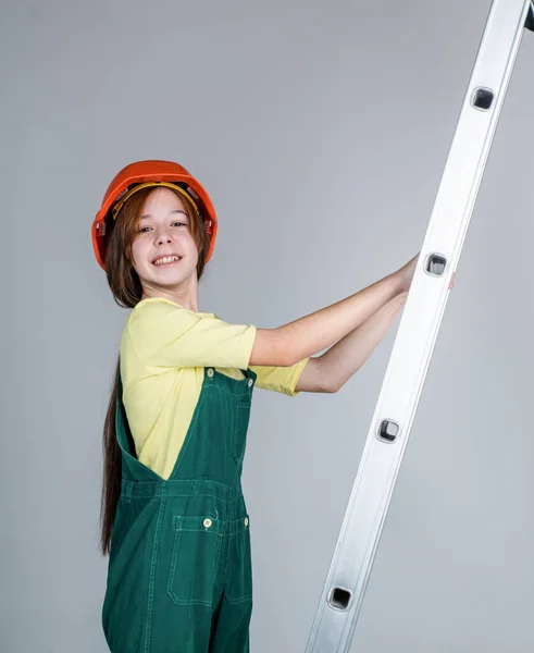 Menina criança em chapéu duro no local de construção uso escada, construtor — Fotografia de Stock