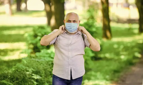 Draag een masker in het park. zorg voor je gezondheid. Bescherm jezelf tegen virussen. Een man met een beschermend masker. lopen buiten op coronavirus quarantaine. let op de voorzorgsmaatregelen tijdens de pandemie. gezond leven — Stockfoto