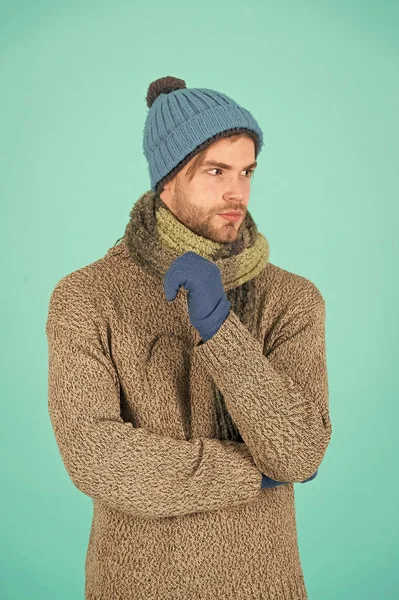 Sıradan bir yakışıklılık. Tıraşsız yakışıklı adam mavi arka planda kış aksesuarları takıyor. Kış sezonu indirimi. Hippi, kış şapkası eşarbı ve eldiven ördü. Alışveriş konsepti. Duygusal ifade