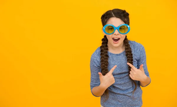 Felice ragazza adolescente con capelli intrecciati indossare occhiali da sole su sfondo giallo, spazio copia, divertimento festa — Foto Stock