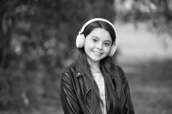 Genießen Sie gute Musik. Glückliches Kind hört Soundtrack im Park. Kleine Mädchen genießen die Musik, die mit Kopfhörern gespielt wird. Stereo-Stereoanlage. Neue Technologie. Modernes Leben. Perfekter Tag braucht perfekten Sound — Stockfoto