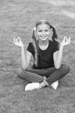 Küçük tatlı kız at kuyruğu saç stili yeşil çimlerde dinlenme, meditasyon konsepti.