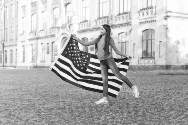 Little girl with american flag outdoors architecture background, national consciousness concept