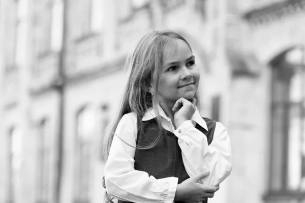 Criança pequena feliz perdida em pensamentos com olhar pensativo em uniforme escolar ao ar livre, pensando — Fotografia de Stock