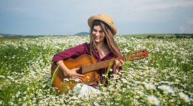 Hafta sonunun tadını çıkarıyorum. Tatil. Özgürlük duygusu. Güzel bir kadın papatya çiçeği tarlasında gitar çalıyor. Yaz ya da bahar doğası. Mevsimsel güzellik. Şapkalı genç kız Meadow 'da country müzik çalıyor.