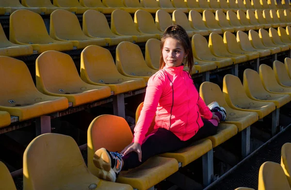 Nastolatka dziewczyna siedzieć w split na odkryty stadion trybuna, gimnastyczka — Zdjęcie stockowe