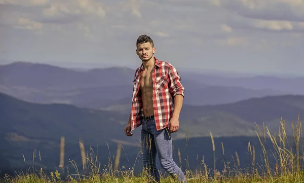 Kräftiger muskulöser Oberkörper des Wanderers. Athletischer muskulöser Kerl entspannen Berge. Wanderkonzept. Macht der Natur. Mann knöpft Hemd stehen oben Berglandschaft Hintergrund. Muskulöser Touristenspaziergang — Stockfoto