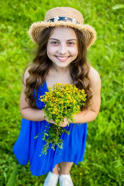 Glad liten unge bära sol hatt på lång väg hår och mode sommar klänning hålla blommor, gåva — Stockfoto