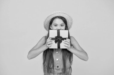 Kendi kutunu tasarla. Küçük kız hediye kutusunu sarı arka planda tutuyor. Tatil kutlaması. Doğum günü yıldönümü. Paket mi paket mi? Hediyelik eşya dükkanı. Alışverişe. Teslimat hazır. Kurdeleyi kutunun etrafına bağla