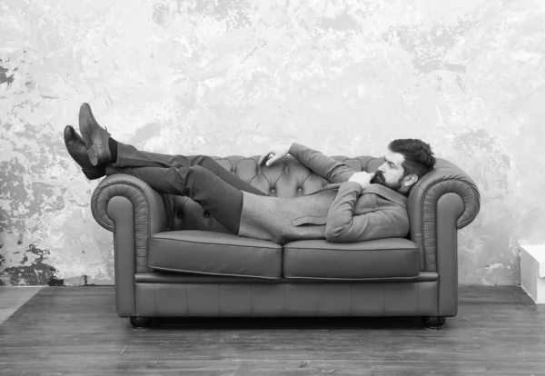 Hombre relajante en lujoso sofá de cuero, concepto de estado de ánimo reflexivo — Foto de Stock